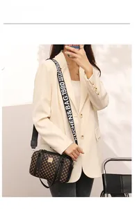 Crossbody bag with brown polka dots and branded wide strap shown on a model