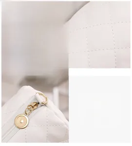 Detailed close-up of white quilted leather texture and golden metal zipper hardware