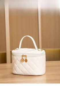 Détail de la trousse de maquillage blanche matelassée avec fermetures éclair dorées