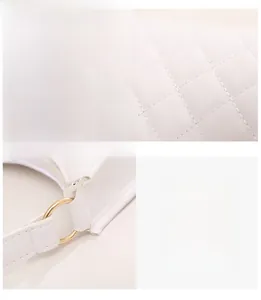 Detail of white quilted faux leather texture and gold-tone metal hardware ring on a handbag