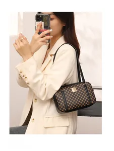 Chic monogram print handbag with golden metal plaque shown in a stylish mirror selfie