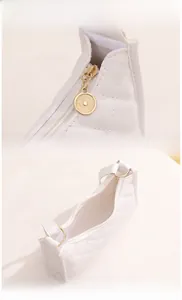 Detail view of the white quilted shoulder bag showing smooth zipper and gold hardware