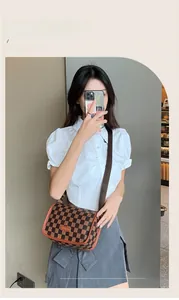 Detalle de bolso bandolera con estampado de cuadros y correa marrón en una modelo