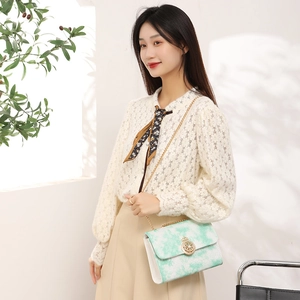 Elegant white crossbody bag with green marble flap and gold chain strap shown on model