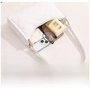 Internal storage view of white quilted shoulder bag holding smartphone and sunglasses