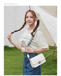 White woven texture crossbody bag with gold buckle and graphic wide shoulder strap