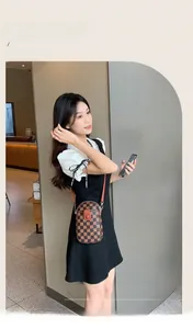Detailed view of checkered mini crossbody phone bag worn by a model in modern interior