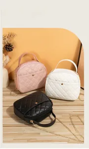 Close-up of three quilted leather crossbody bags in pink, white and black colors