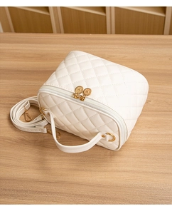 Détail du sac à main matelassé blanc avec fermetures dorées et poignée supérieure