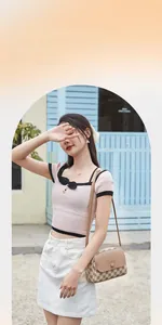 Outdoor shot of a beige plaid shoulder bag with a round buckle on a model