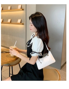 Detail of white quilted rhombus shoulder bag with gold hardware and warm lighting