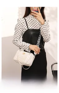Detail of white quilted crossbody bag with golden hardware and two adjustable straps