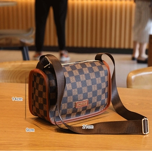 Détail d'un sac bandoulière à damier avec dimensions 21cm x 14cm sur une table