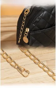 Detail of black quilted shoulder bag featuring gold chain strap and polished side zipper