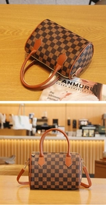 Close-up of checkerboard Boston bag with leather handles and detachable strap on wood