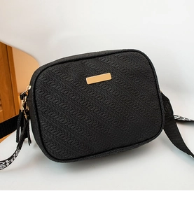 Detailed view of black embossed women's camera bag featuring stylish gold hardware