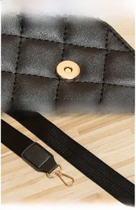 Detail of embroidered diamond lattice pattern on black bag with gold hardware