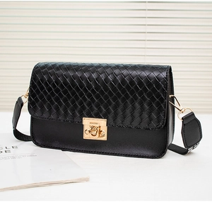Detail of black woven flap bag with gold turn-lock closure and wide canvas strap