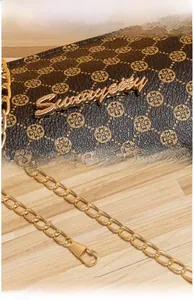 Detail of dark brown leather cylinder bag with gold logo and metal chain strap