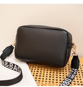 Détail du sac bandoulière en similicuir noir avec bandoulière large et boucles dorées