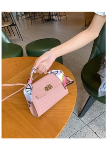 Detail der rosa gesteppten Handtasche mit goldenem Drehverschluss und Seidenschal