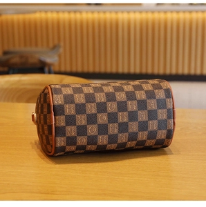 Detailed view of cylindrical barrel bag with brown checkerboard pattern on wooden desk