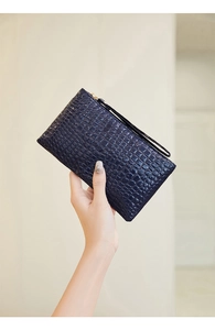 Navy blue clutch bag featuring crocodile texture and gold zipper with wristlet strap