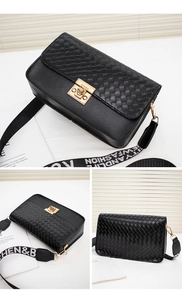 Detailed close-up of a black woven crossbody bag with metallic clasp and wide strap