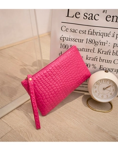 Close-up of rose red crocodile embossed texture on a synthetic leather wristlet pouch