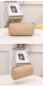 Detailed close-up of beige quilted cylinder bag with gold chain strap and zipper