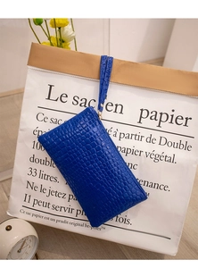 Detail of blue faux crocodile leather clutch purse with gold zipper and wrist strap