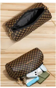 Interior storage space of brown quilted cylinder bag showing phone and cosmetics