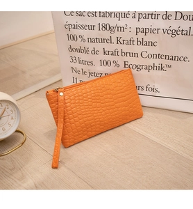 Orange crocodile-patterned clutch bag with golden zipper and wristlet detail