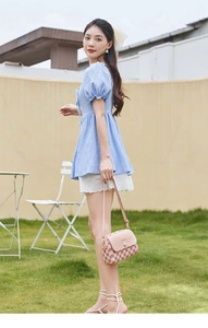 Pink checkered crossbody bag styled with pastel outfit against a bright garden background
