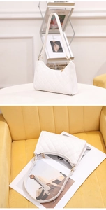Detail of white quilted hobo bag featuring gold metal rings and elegant zipper closure