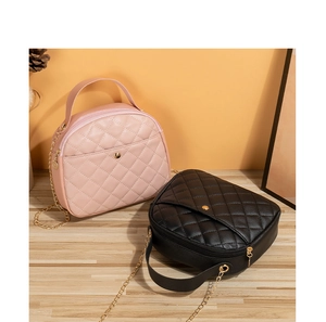Detail of pink and black quilted crossbody bags with chain straps on wooden surface