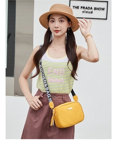 Detail of yellow woven crossbody bag with adjustable wide lettered shoulder strap