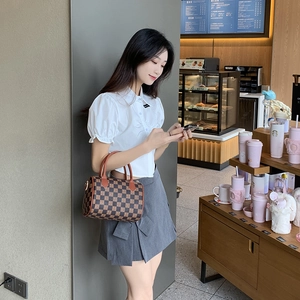 Vintage checkered print Boston bag with leather handles shown in a lifestyle cafe setting