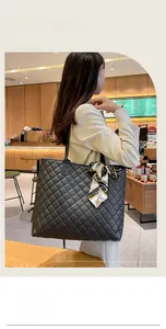 Gros plan d'un grand sac cabas noir matelassé orné d'un foulard en soie chic
