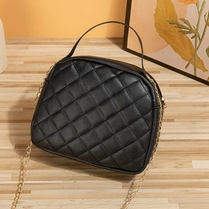 Elegant black quilted handbag with golden chain strap and leather handle on wooden surface