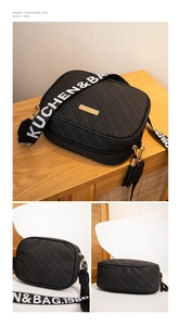 Detail view of black textured camera bag featuring a wide woven strap and fringe tassel charm