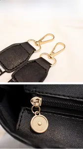 Detail of golden metal lobster clasp and zipper on black lychee grain leather bag
