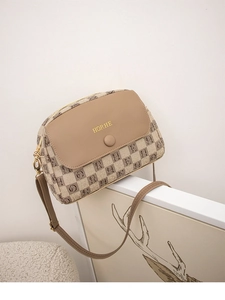 Detail view of brown PU leather and canvas crossbody bag with letter print on a display