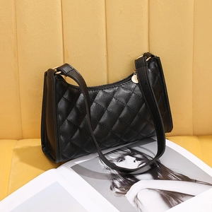 Quilted black faux leather shoulder bag with gold hardware on a stylish magazine
