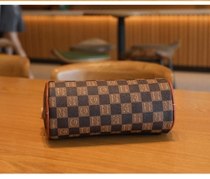 Makro-Detail der braunen Zylindertasche mit Schachbrettmuster und Vintage-Schriftzug