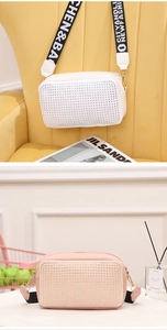 Détail de sacs bandoulière cloutés blanc et rose avec de larges bandoulières à motifs
