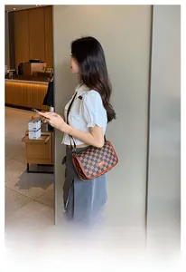 Bolso bandolera a cuadros marrones con correa ajustable llevado por modelo en café