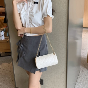 White quilted cylinder shoulder bag with gold chain strap shown on a model