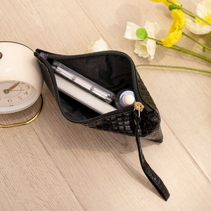Minimalist black crocodile pattern clutch bag with internal cosmetics storage on wooden table