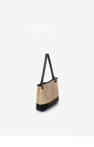 Detail of minimalist straw tote bag featuring contrast black trim and a woven texture